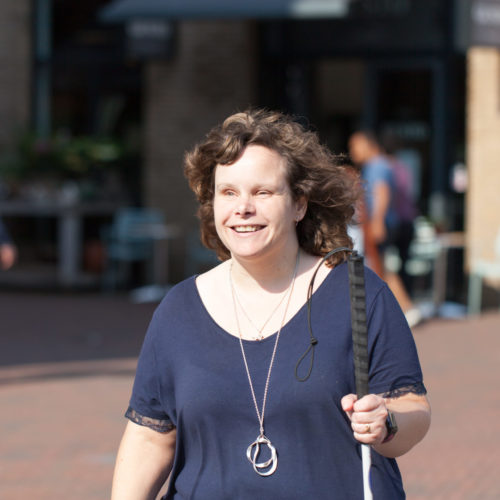 Marjolein op straat met haar geleidestok in haar hand